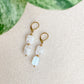 Détail des boucles d’oreilles Phoebe en pierre de lune arc-en-ciel et acier inoxydable doré, photographiées en gros plan.