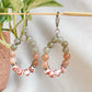 Boucles d’oreilles Capri en pierres naturelles pendantes, montées à la main à Montréal, suspendues sur support décoratif.