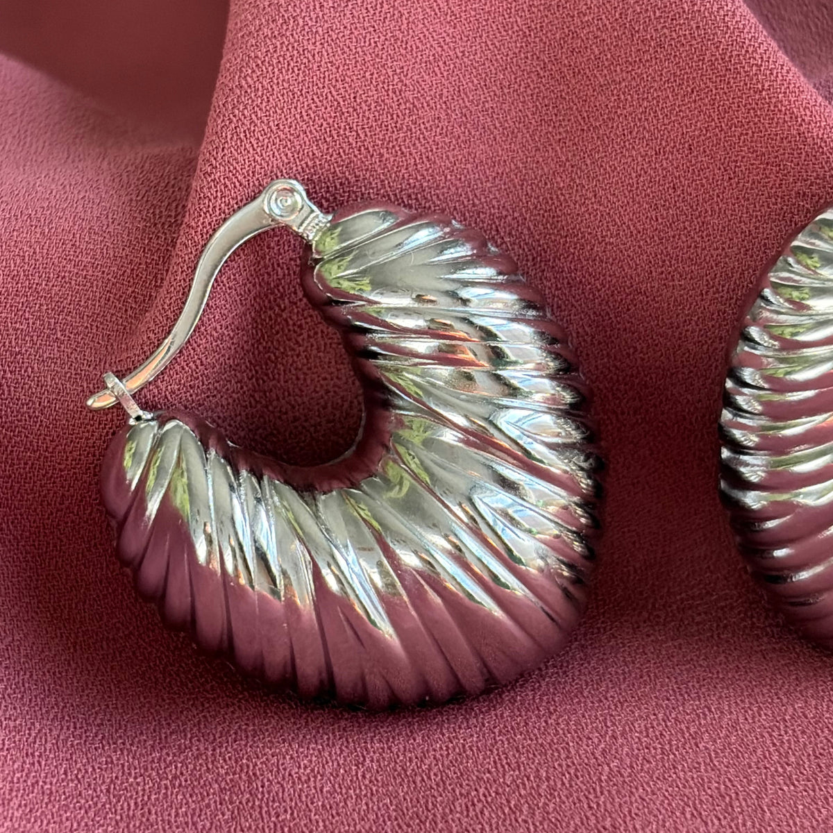 Détail de la texture ondulée des boucles d’oreilles Sirocco argentées