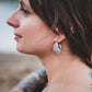 Boucles d’oreilles Sirocco argentées portées dans un décor naturel