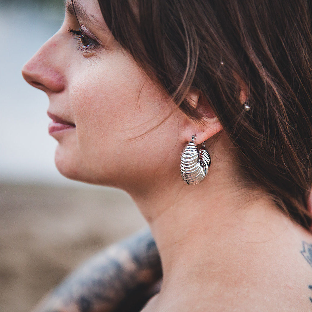 Boucles d’oreilles Sirocco argentées portées dans un décor naturel