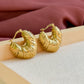Détail de la texture ondulée des boucles d’oreilles Sirocco dorées