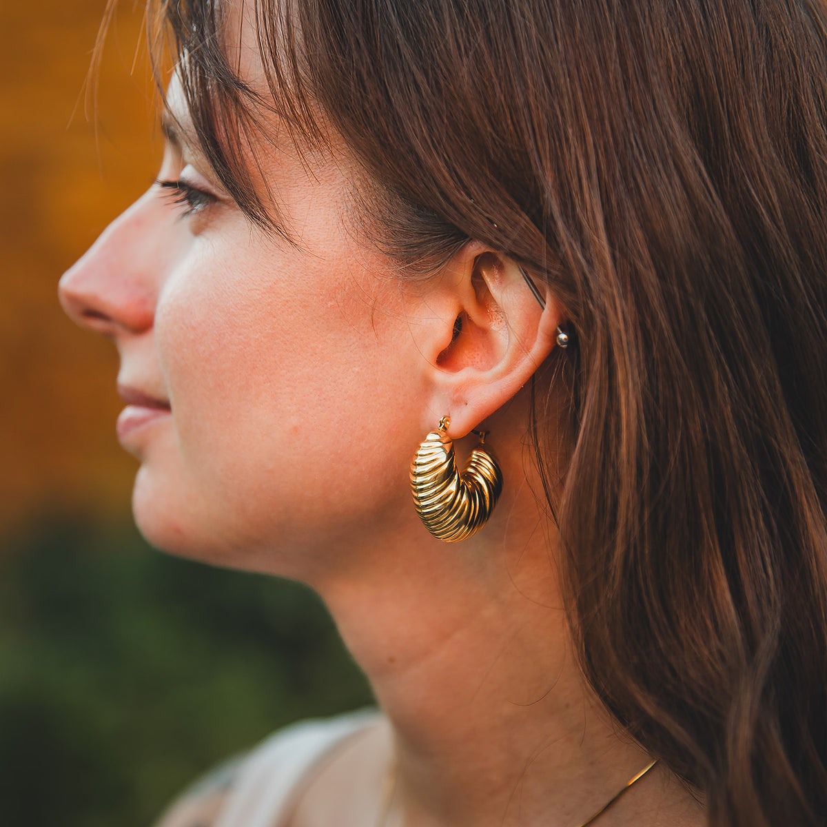 Boucles d’oreilles Sirocco dorées portées, vues de profil
