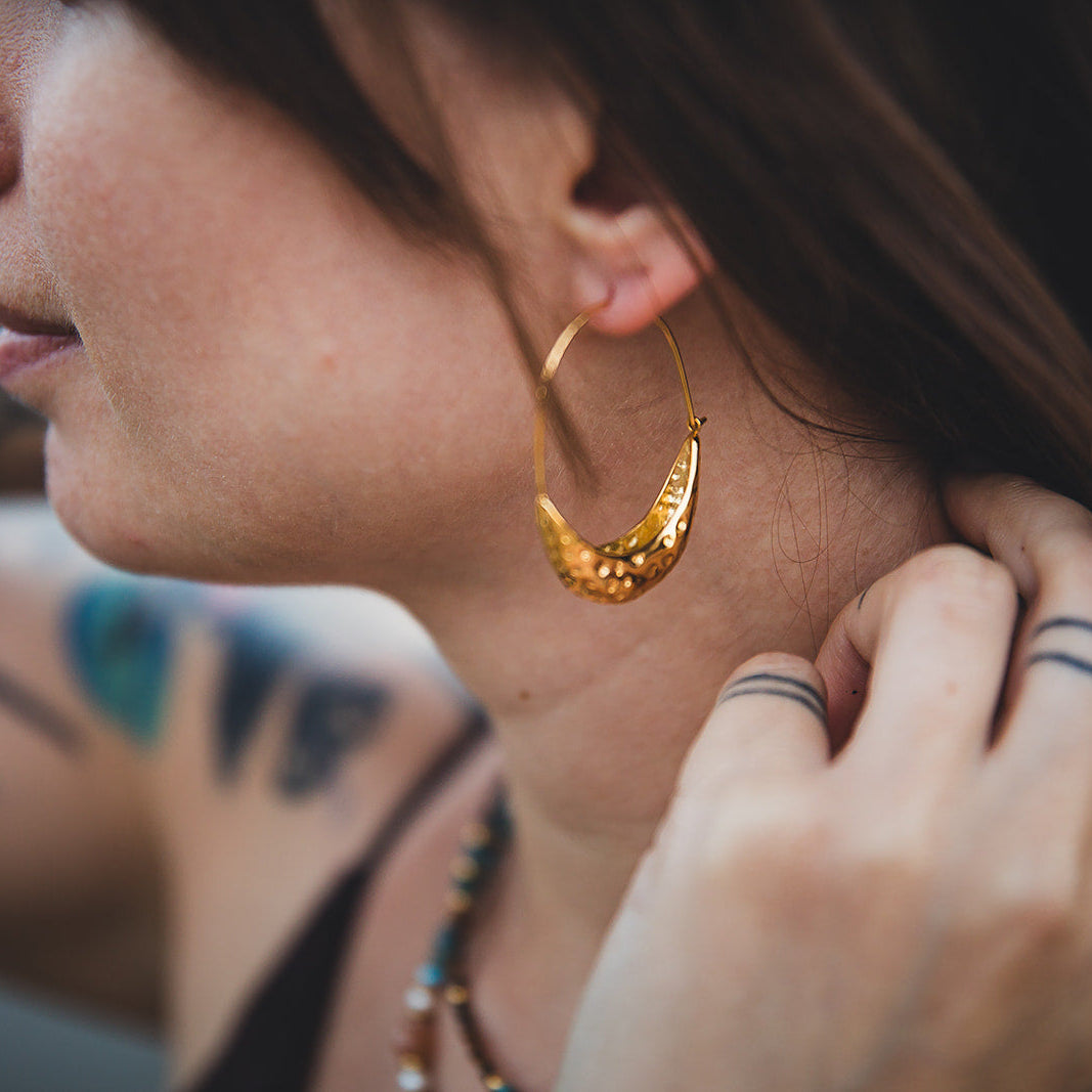 Gros plan des boucles d’oreilles Souk dorées portées