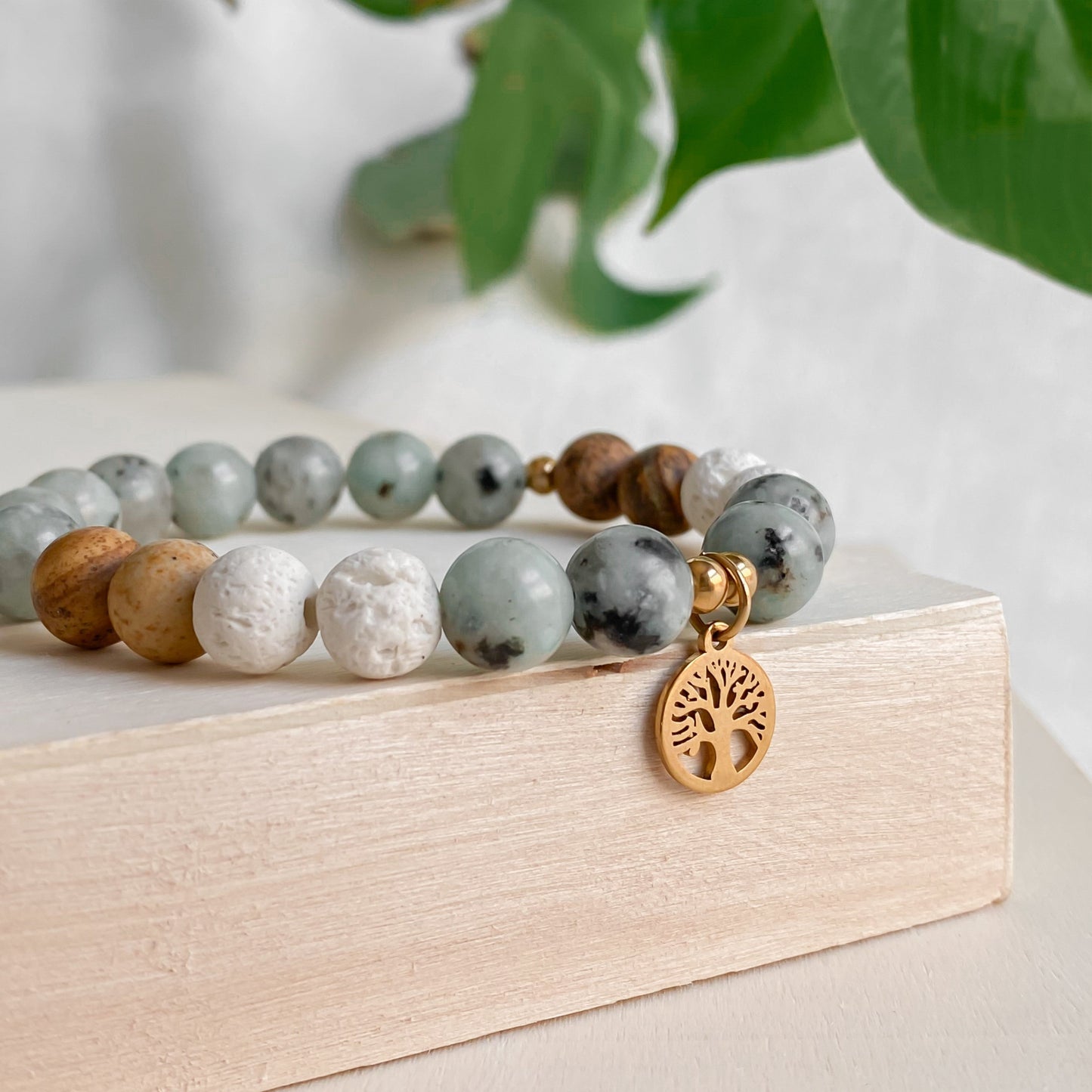 Zoom sur le bracelet Arbre de Vie, composé de pierres semi-précieuses de Jaspe kiwi, Jaspe paysage et pierres de lave blanche, avec breloque arbre de vie, symbolisant la sérénité et la force.