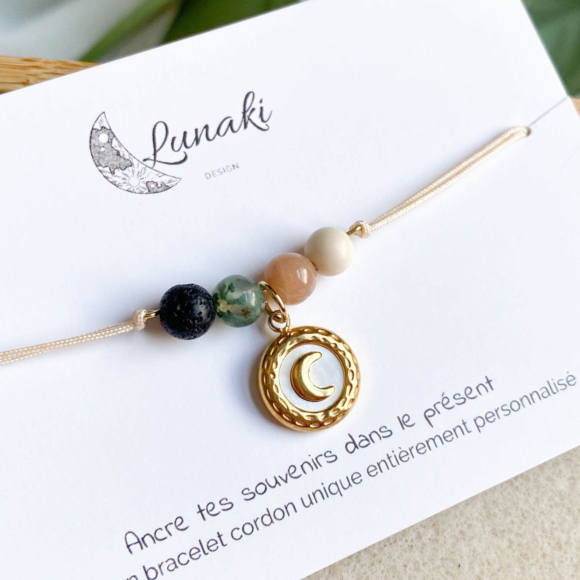 Gros plan sur le bracelet cordon L'Essentiel en acier inoxydable doré avec breloque lune, mettant en valeur les détails du design et l'éclat du métal.