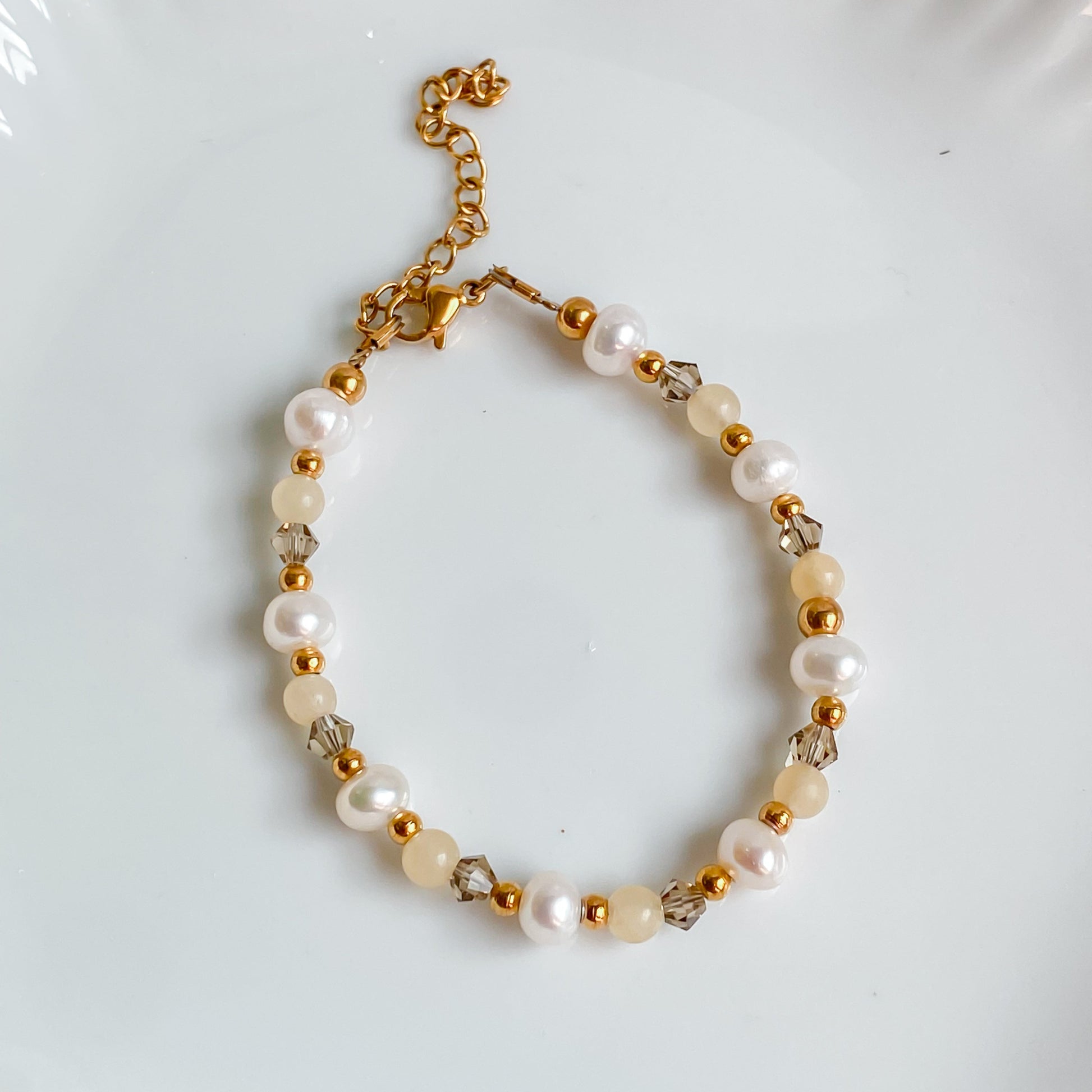 Bracelet fin en pierres de jade jaune, perles d’eau douce et cristaux fumés, monté sur acier inoxydable doré.