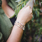 Femme portant le bracelet Hécate en pierres naturelles avec pierre de soleil et perles d’eau douce, look artisanal et doré.