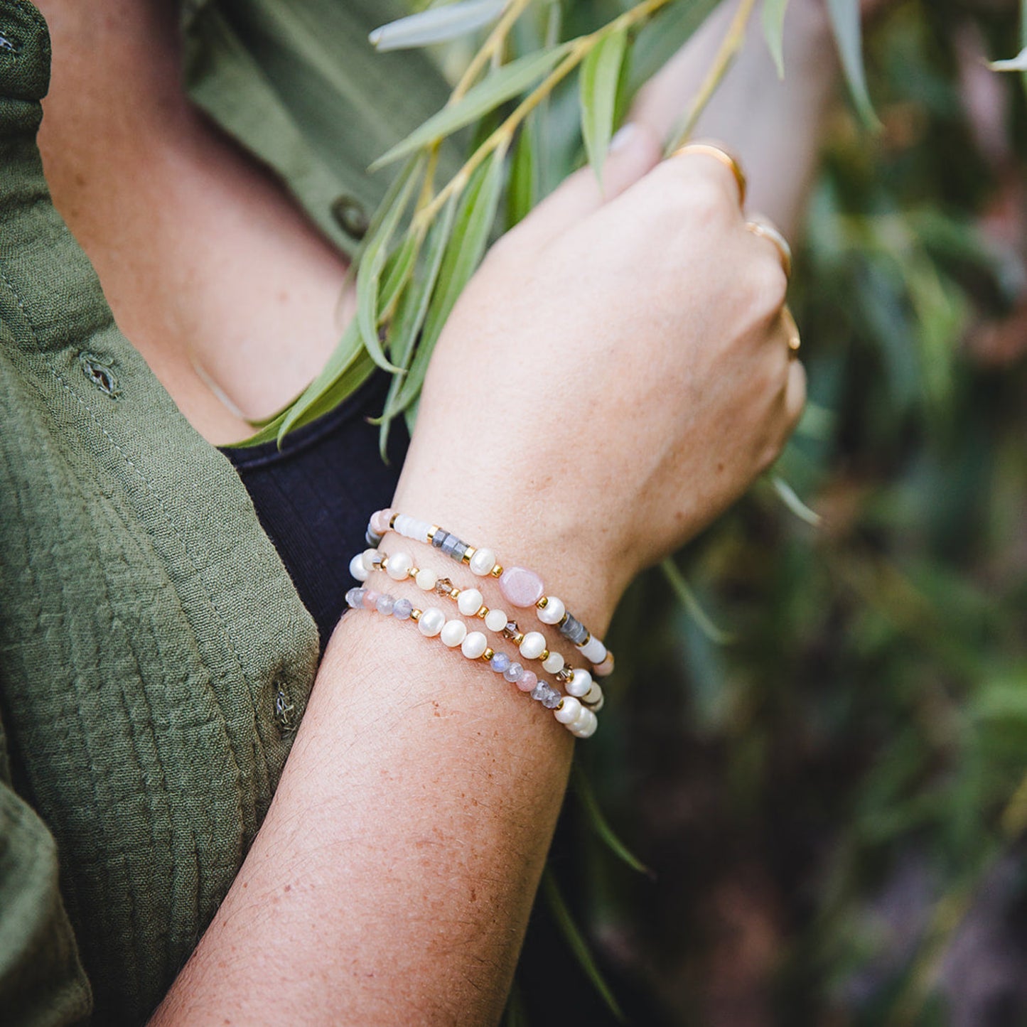 Femme portant le bracelet Hécate en pierres naturelles avec pierre de soleil et perles d’eau douce, look artisanal et doré.