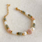 Bracelet Hécate en pierres naturelles avec pierre de soleil, jade blanc, labradorite et perle d’eau douce, sur fond beige.