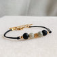 Bracelet NOCTIS en cordon noir avec pierres de lave et labradorite, diffuseur d’huiles essentielles, vue rapprochée sur fond clair.