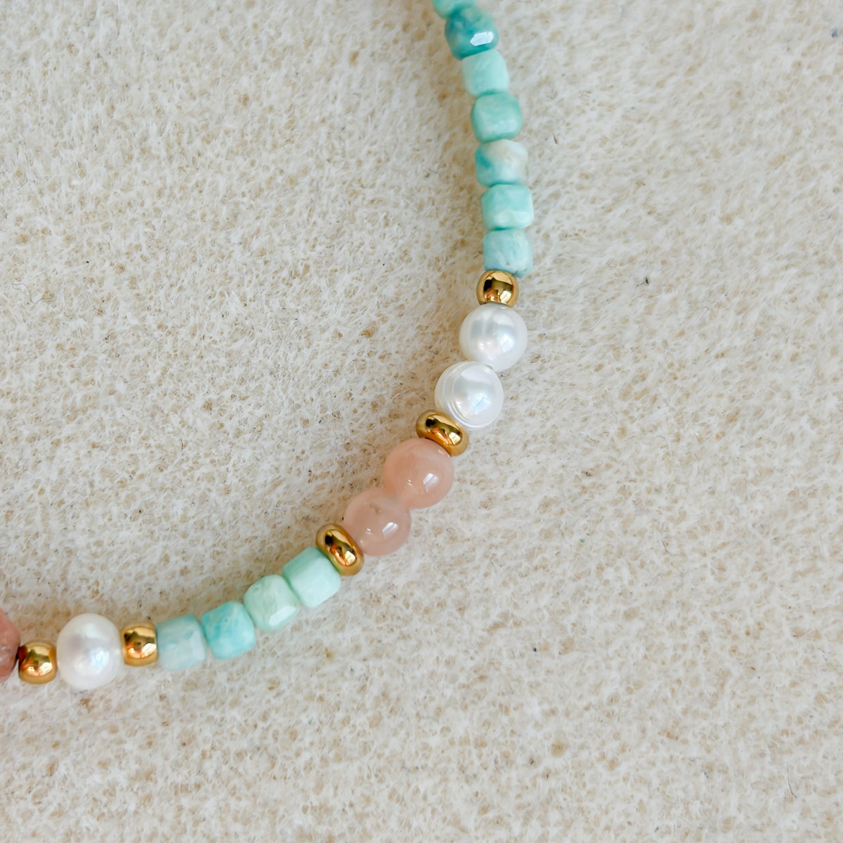 Gros plan sur l’amazonite, la pierre de soleil et les perles d’eau douce du bracelet Riad