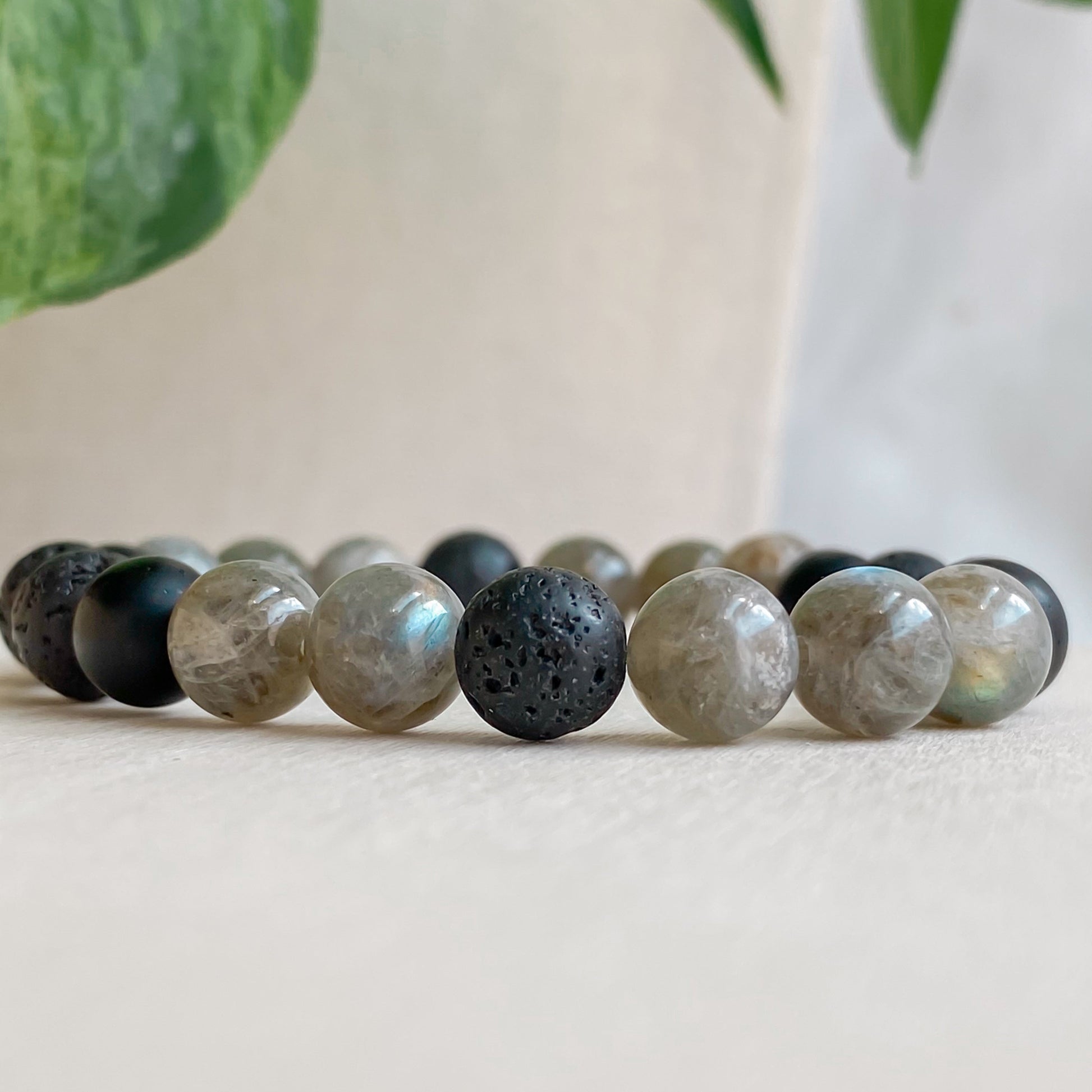 Gros plan du bracelet élastique Serenzo en pierres naturelles (labradorite, lave, onyx) avec acier inoxydable argenté, mettant en valeur les reflets de la labradorite.