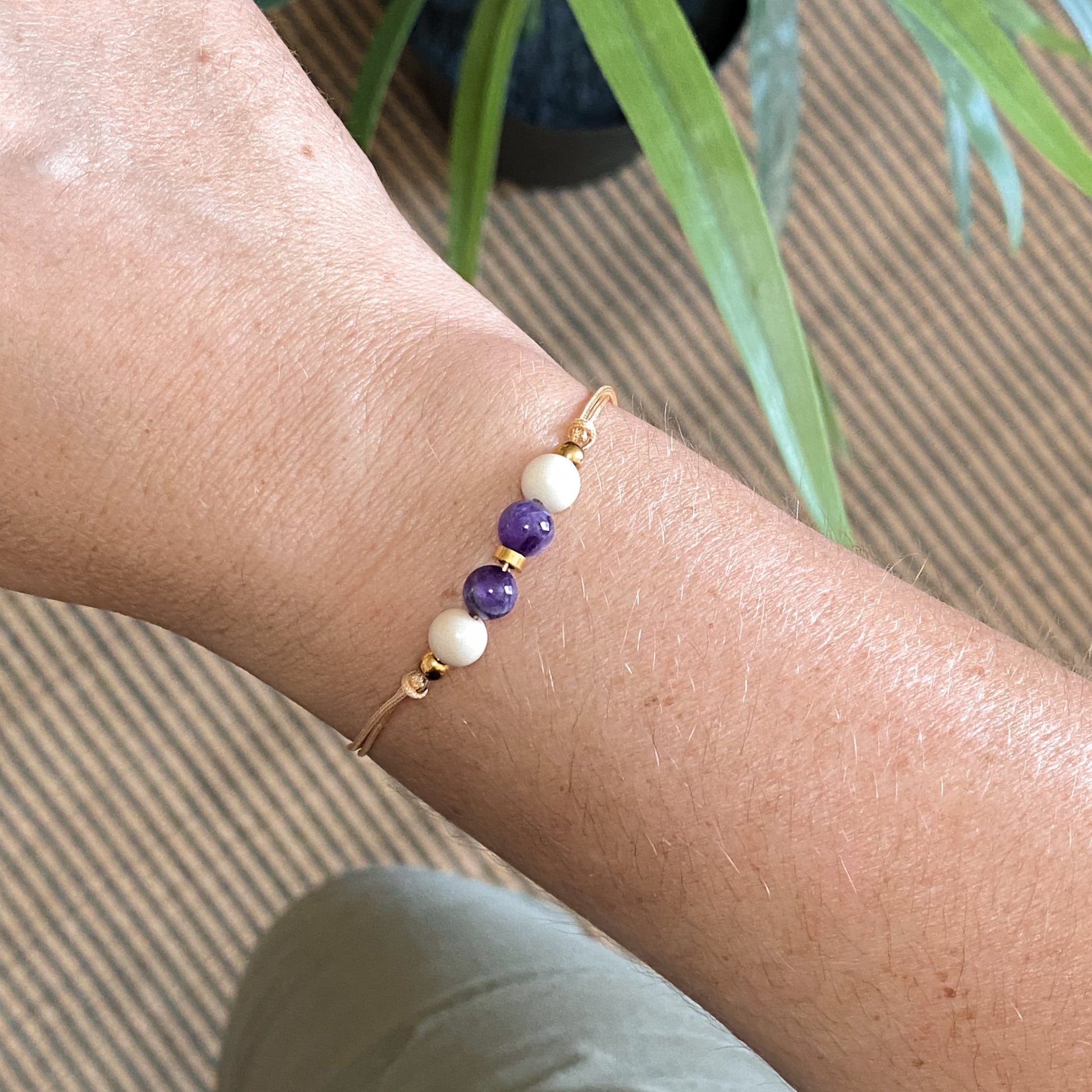 Bracelet Zéphyr en améthyste porté au poignet, bijou artisanal fait main avec cordon ajustable champagne