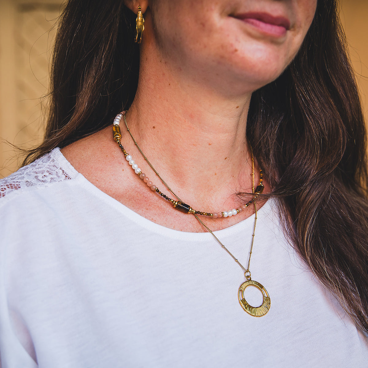 Collier Agafay porté en accumulation avec un collier doré