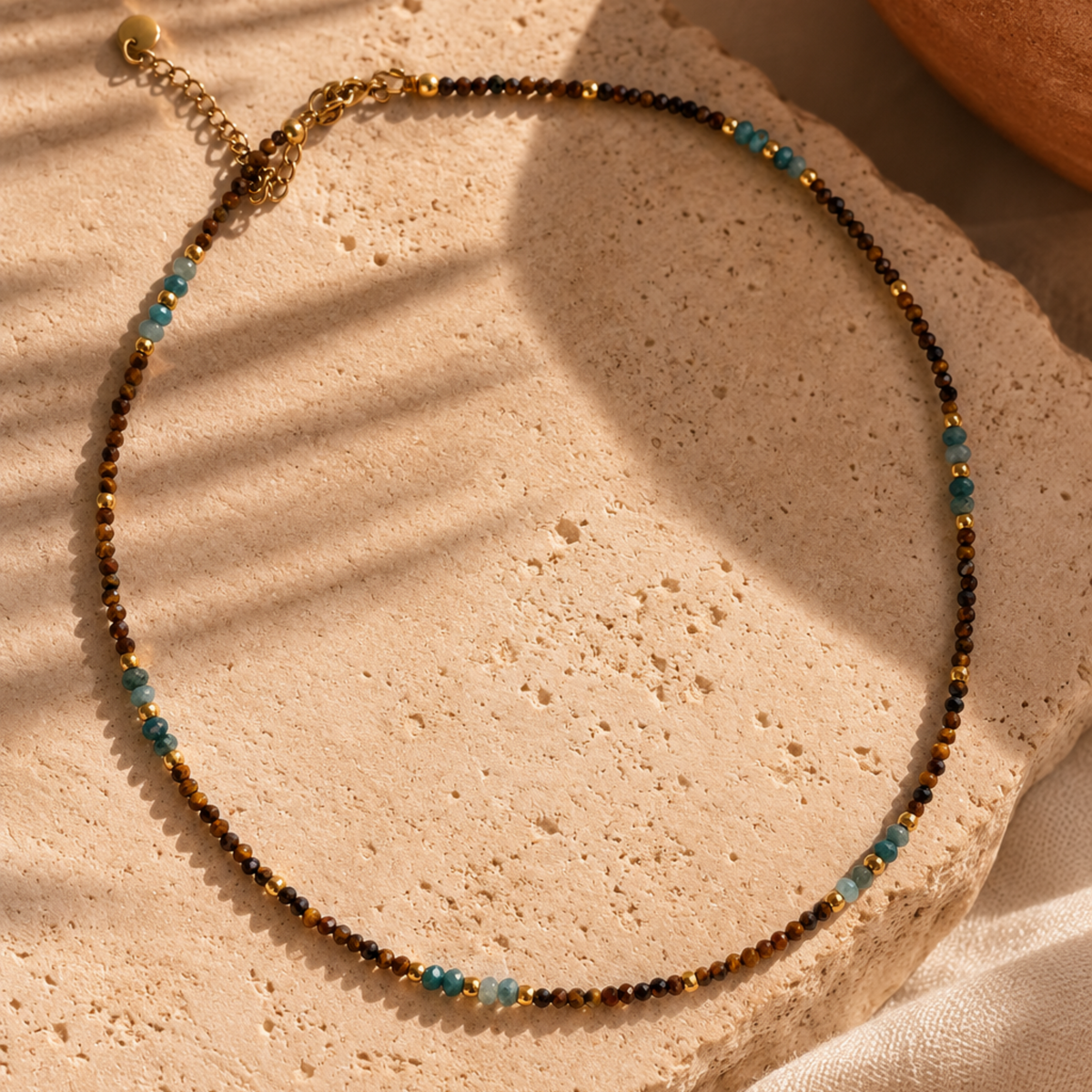Collier Atlas en œil de tigre et apatite présenté dans une ambiance inspirée du Maroc