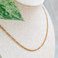 Collier Aurora en acier inoxydable doré 18K présenté sur un présentoir en lin, style minimaliste et intemporel.