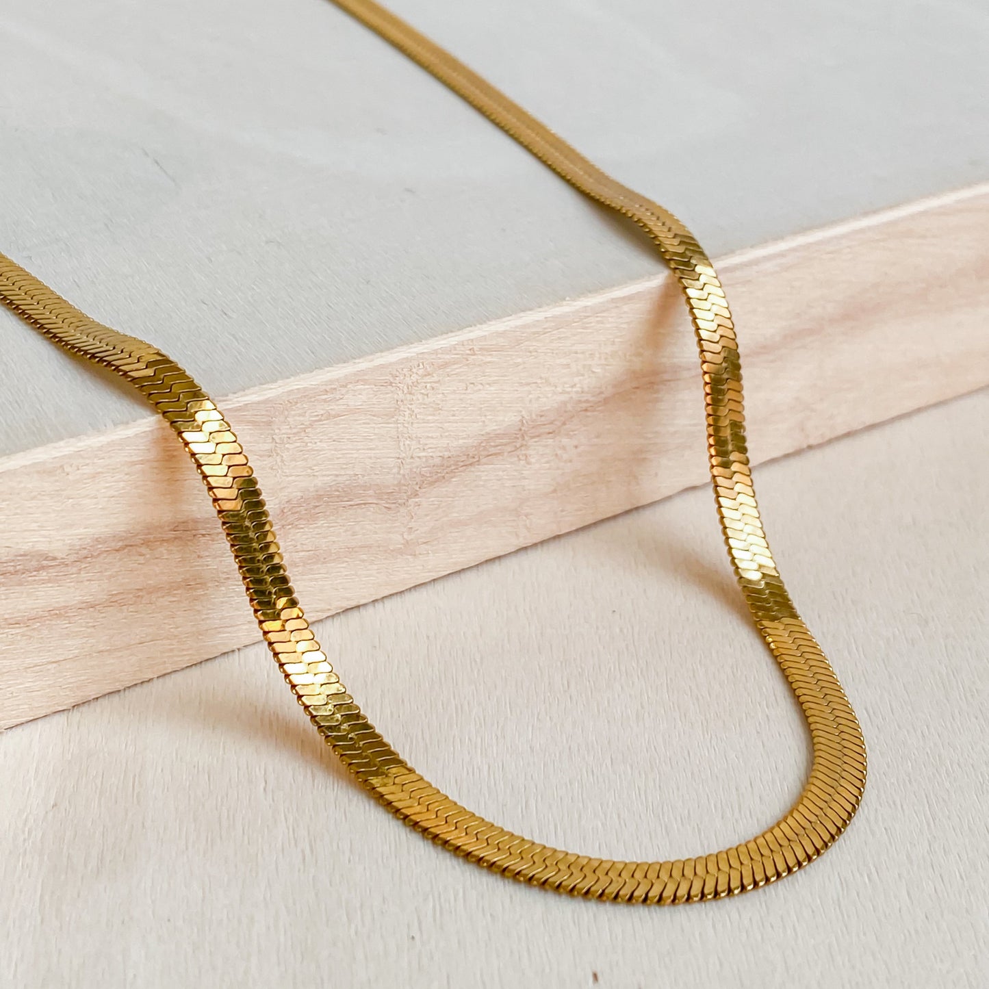 Collier ras de cou Cléopâtre doré en acier inoxydable 18K de Lunaki Design, posé sur bois