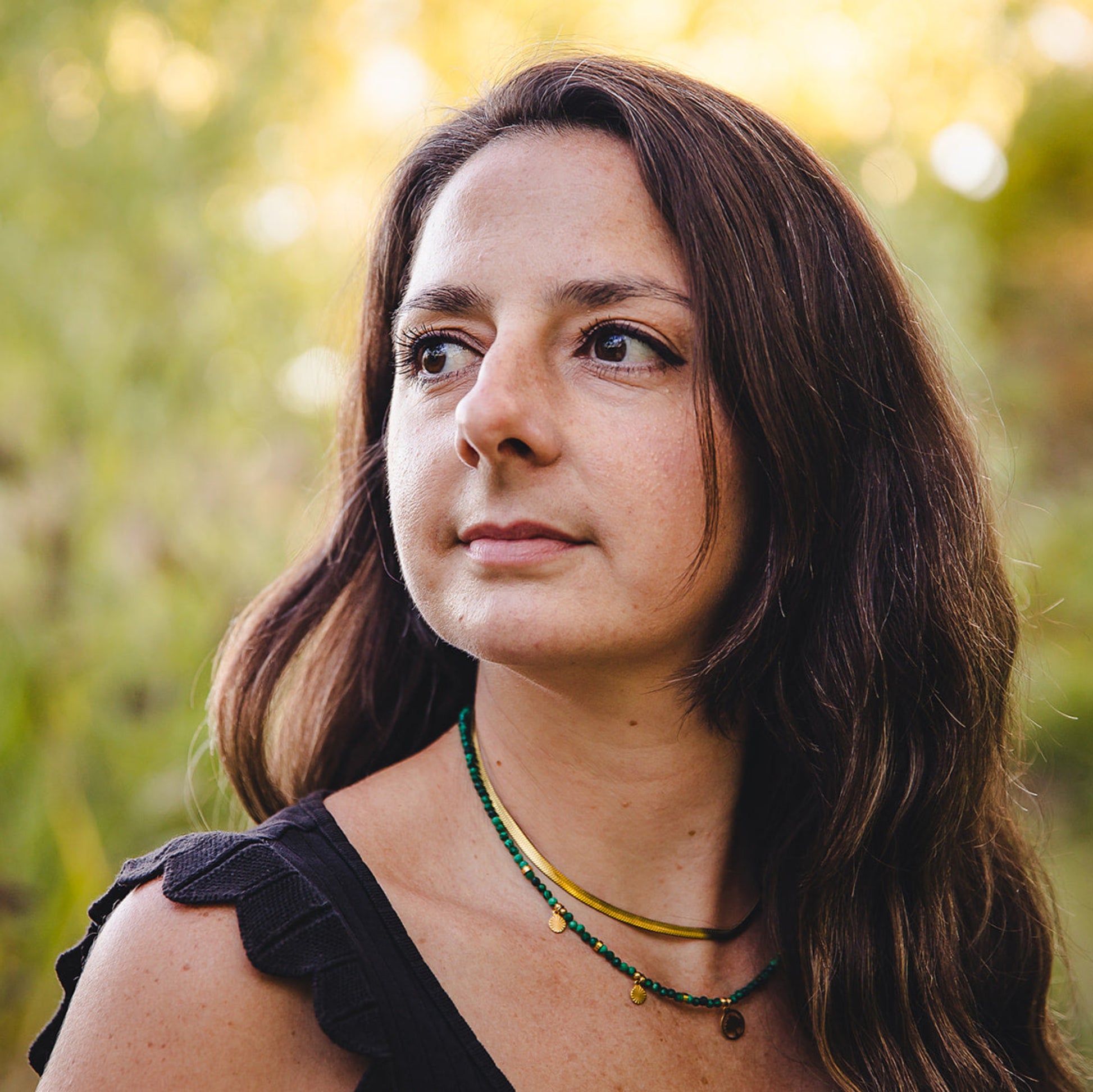 Femme portant le collier Cléopâtre doré en acier inoxydable 18K avec un collier de perles vertes