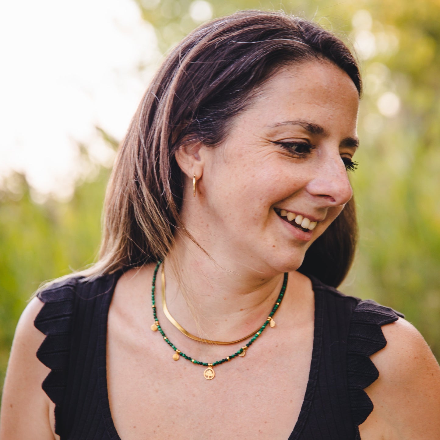 Femme portant le collier Déméter en malachite et acier inoxydable doré, avec pendentif arbre de vie, bijou talisman de la collection Jardin Secret.