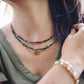 Collier Déméter en malachite avec pendentif arbre de vie porté en superposition avec un autre collier de pierres naturelles.