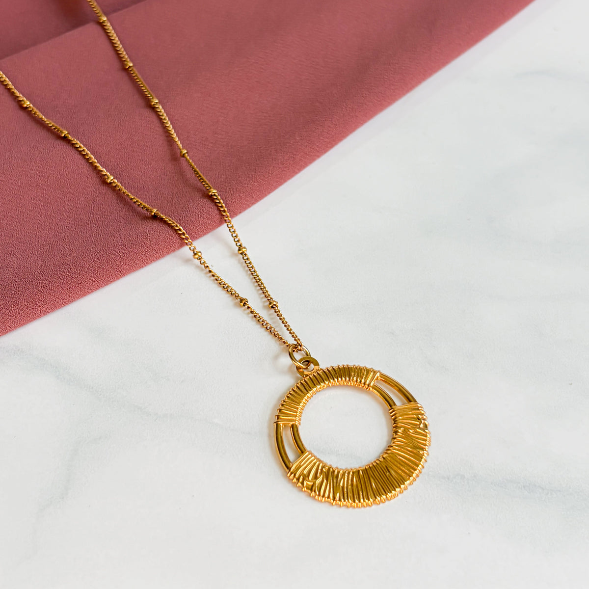 Vue complète de la chaîne et du pendentif rond du collier Escale