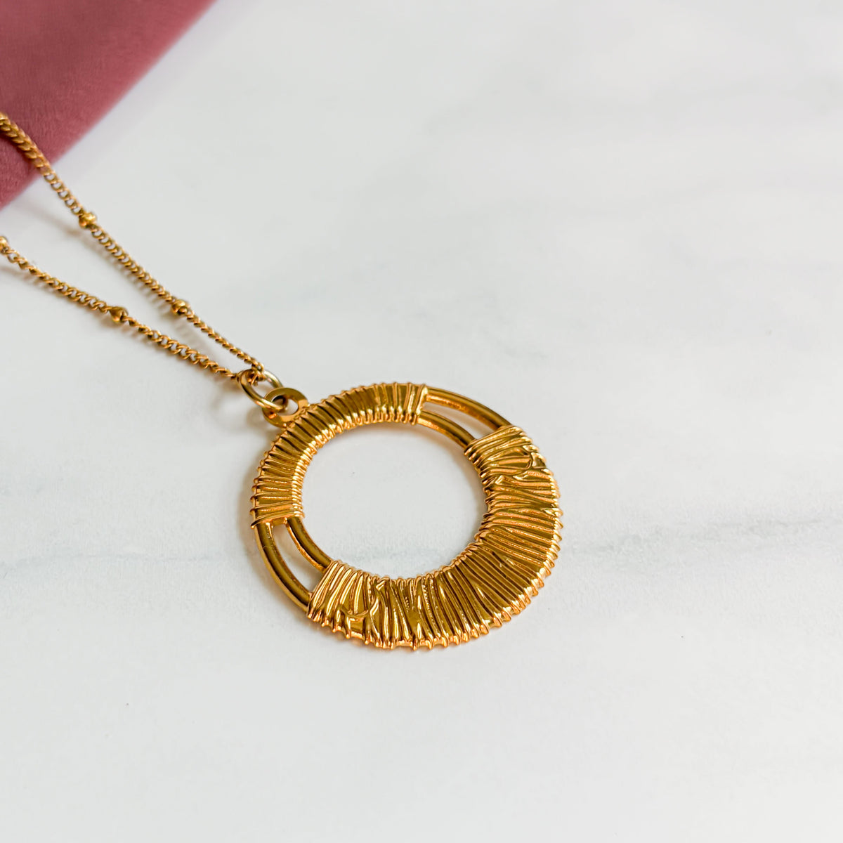 Gros plan de la texture du pendentif rond du collier Escale