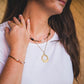 Collier Escale doré porté en accumulation avec un collier de pierres