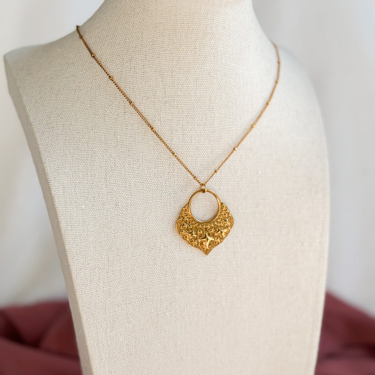 Collier Fanous doré présenté sur un buste