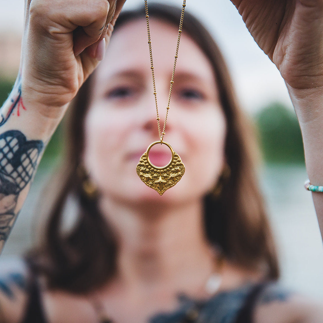 Pendentif étoilé du collier Fanous doré présenté à la main