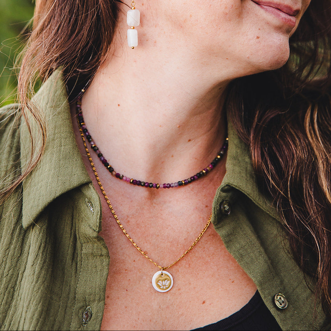 Femme portant le collier Iris en tourmaline naturelle et hématite dorée, associé à un pendentif doré, bijou artisanal de la collection Jardin Secret Lunaki.