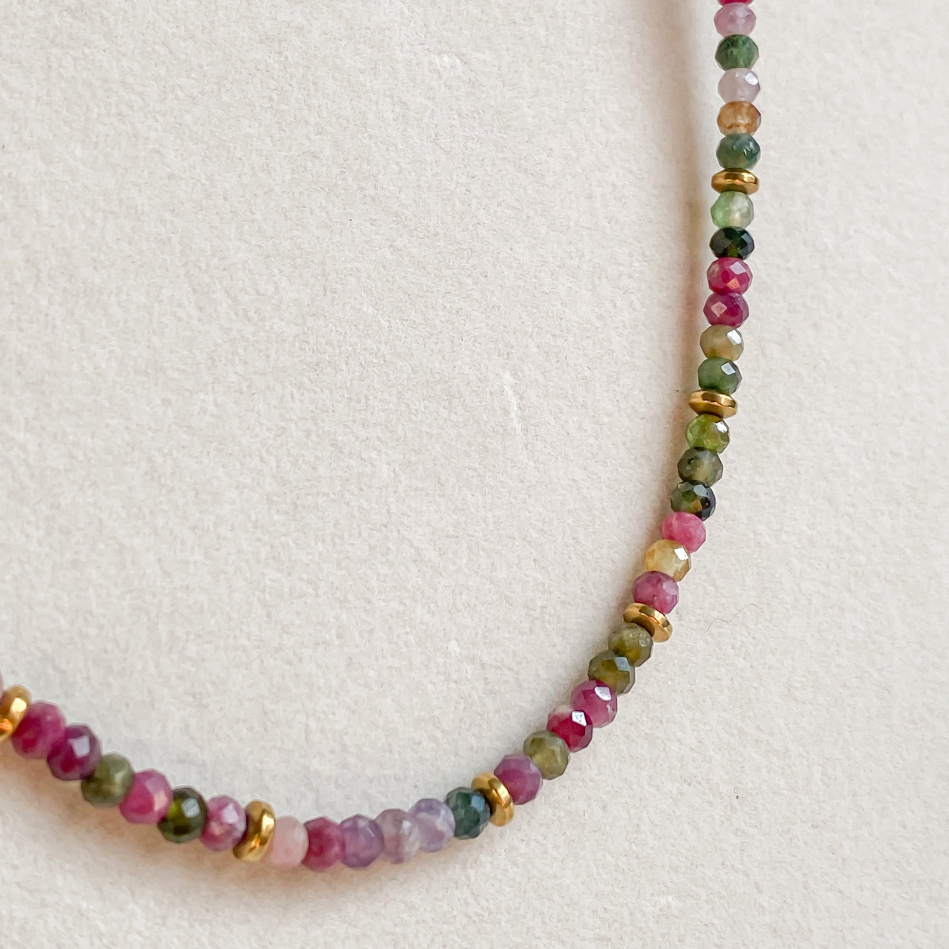 Gros plan du collier Iris en tourmaline multicolore et hématite dorée sur acier inoxydable doré 18K, détail des perles.