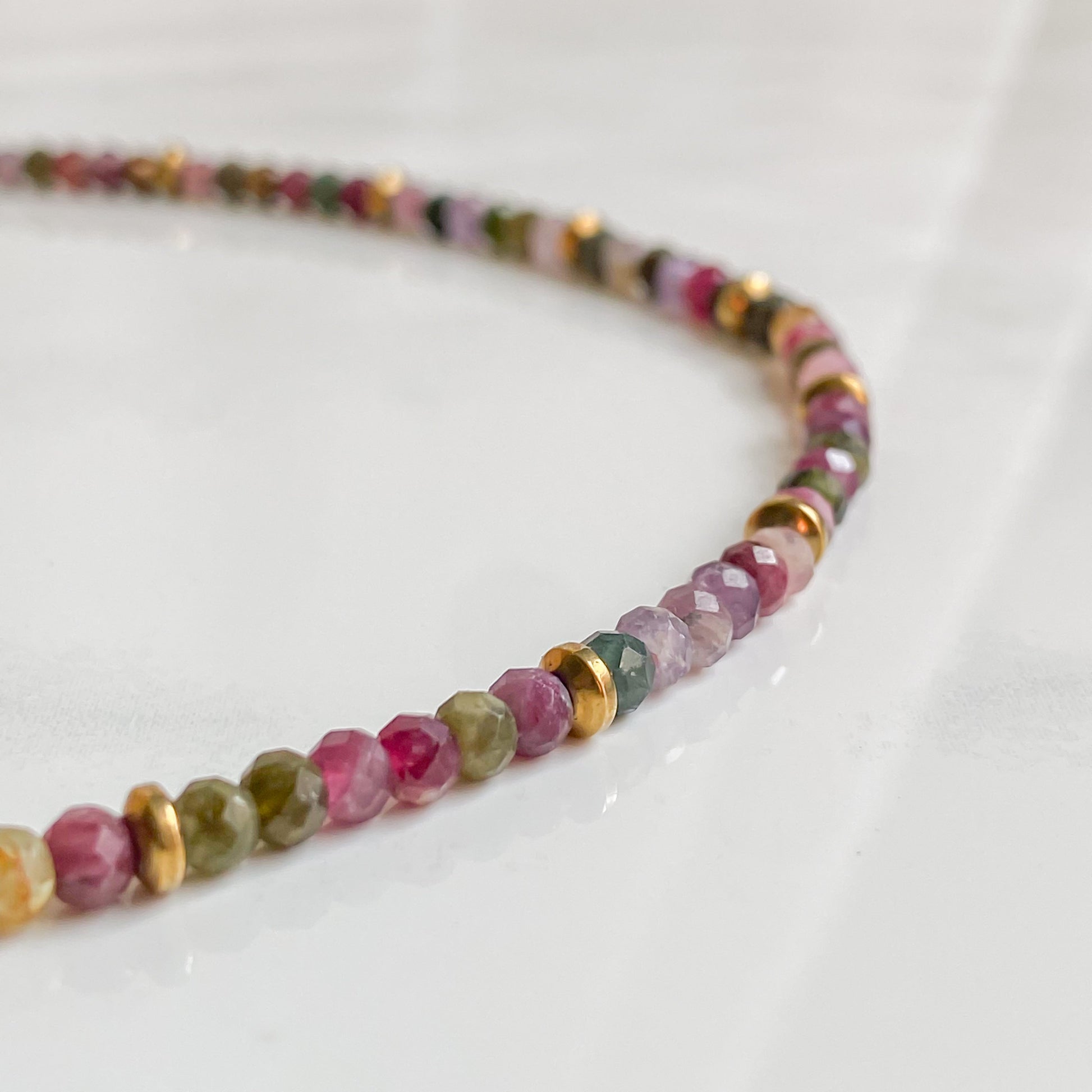 Collier Iris avec perles facettées de tourmaline multicolore et hématite dorée, bijou artisanal en acier inoxydable plaqué or 18K.