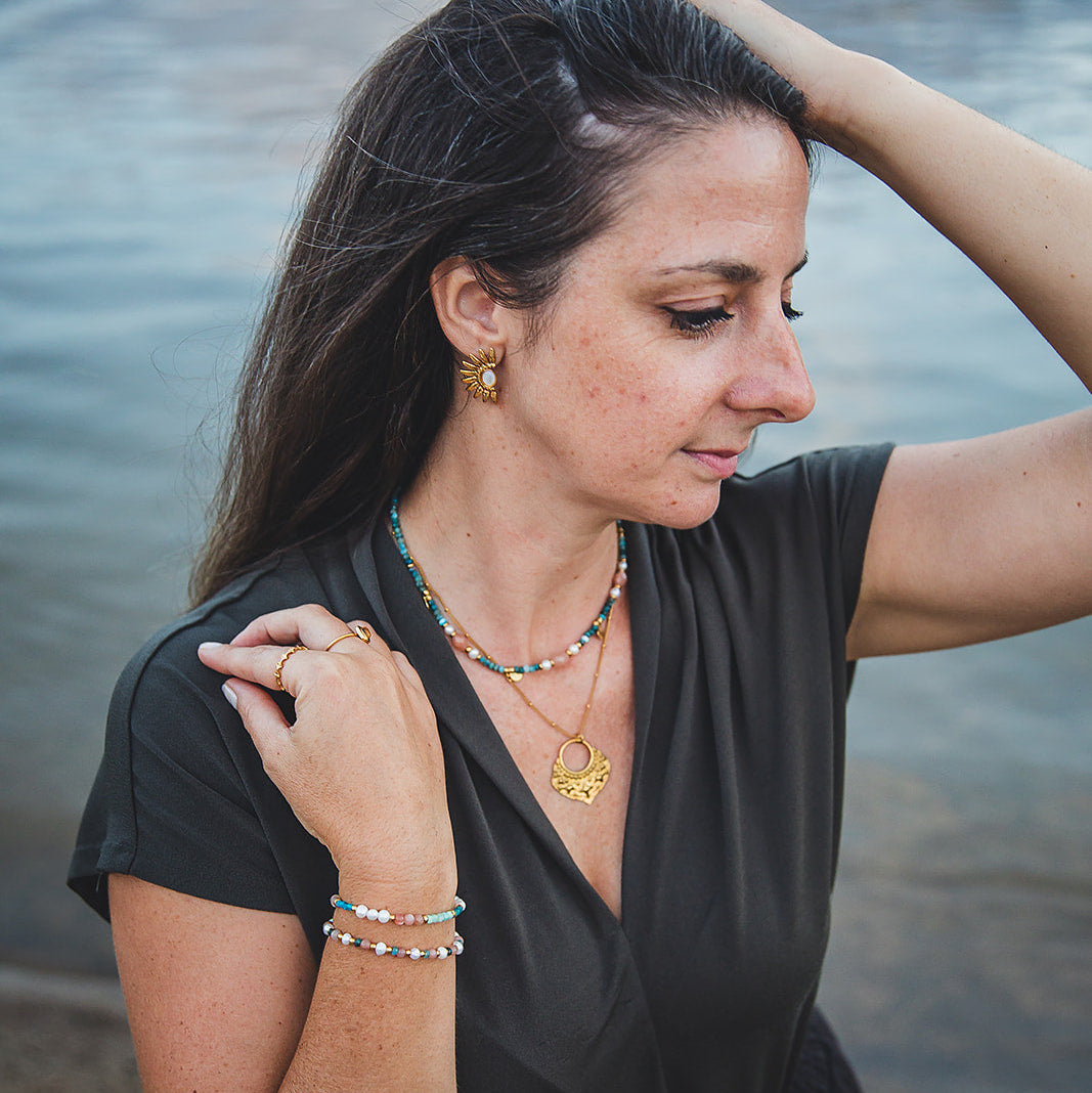 Collier Oasis porté avec un collier doré et des bracelets assortis