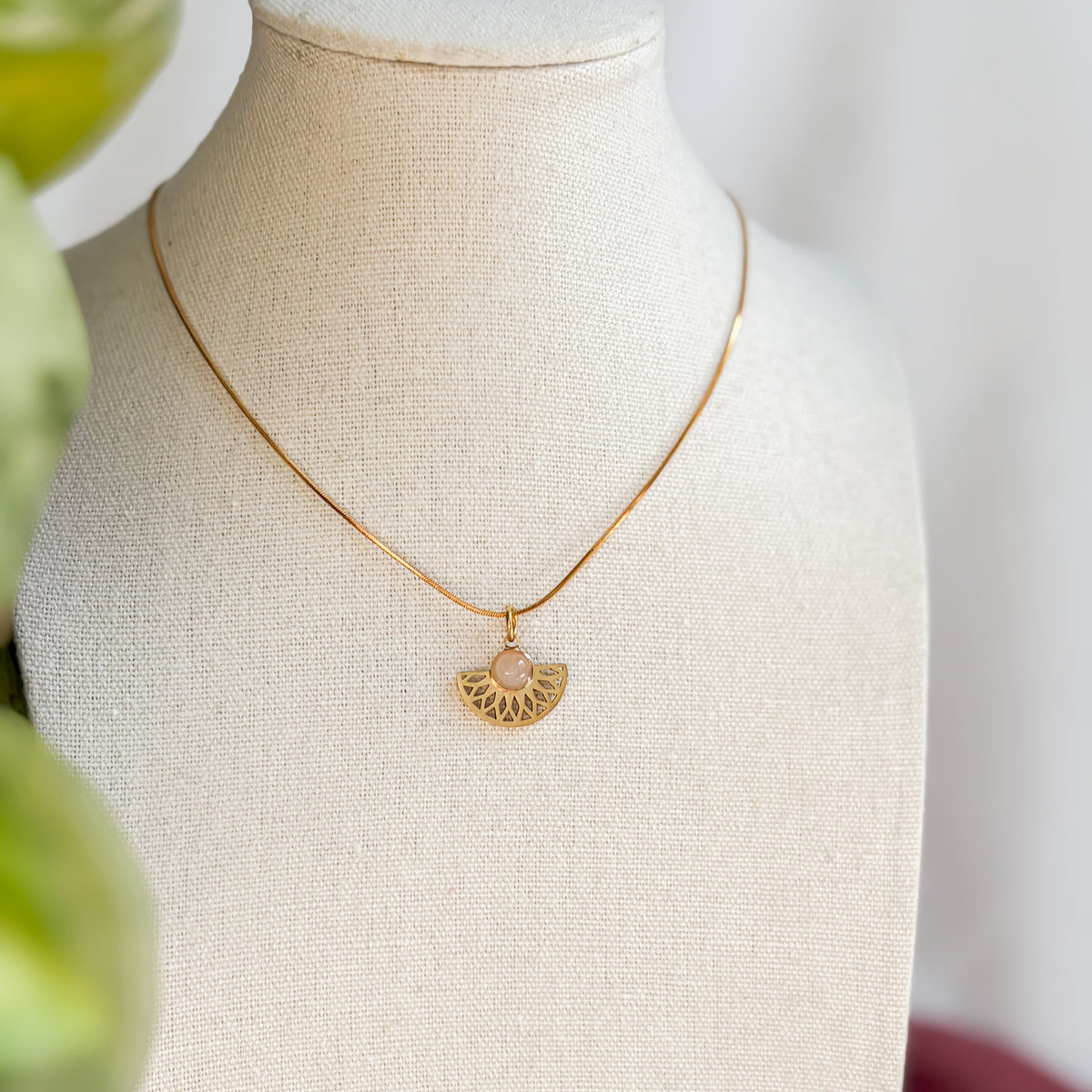 Collier Rosace doré en quartz rose présenté sur un buste