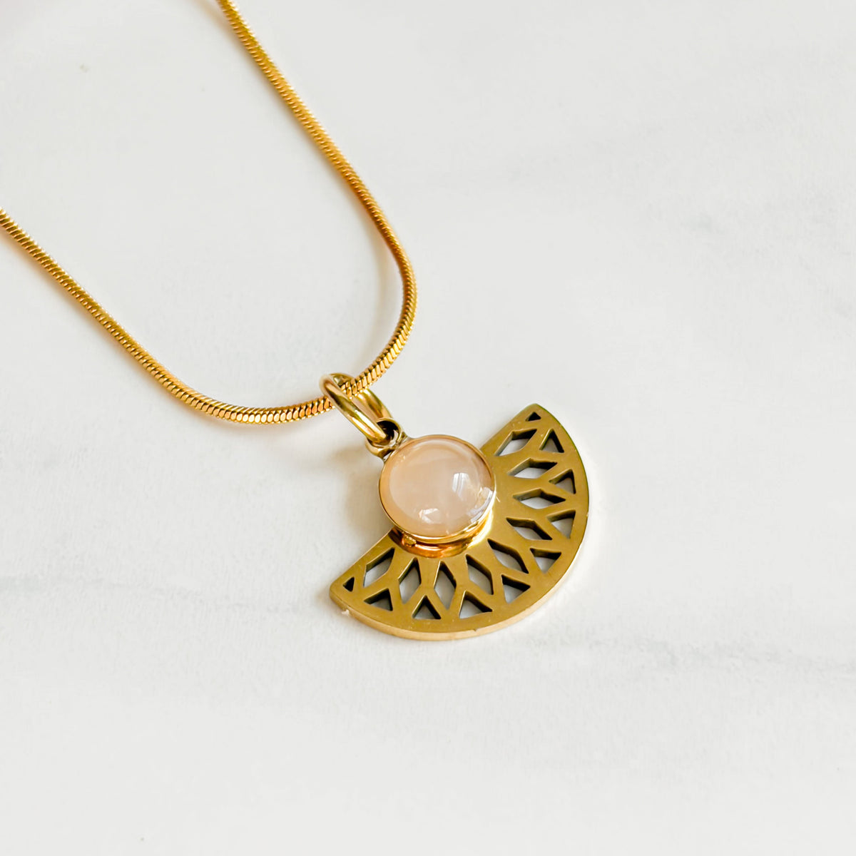 Gros plan du quartz rose et du motif ajouré du collier Rosace