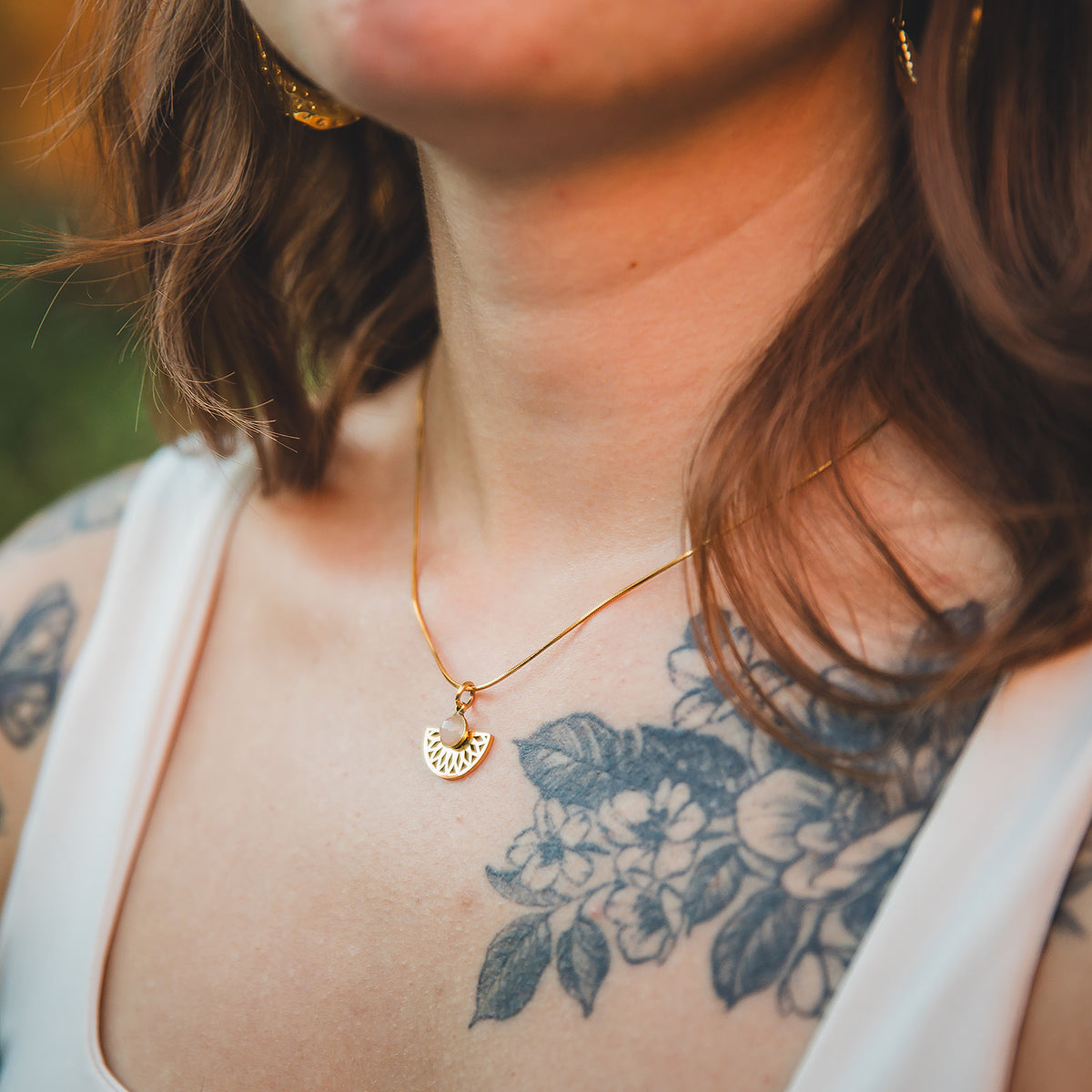 Gros plan du collier Rosace doré en quartz rose porté