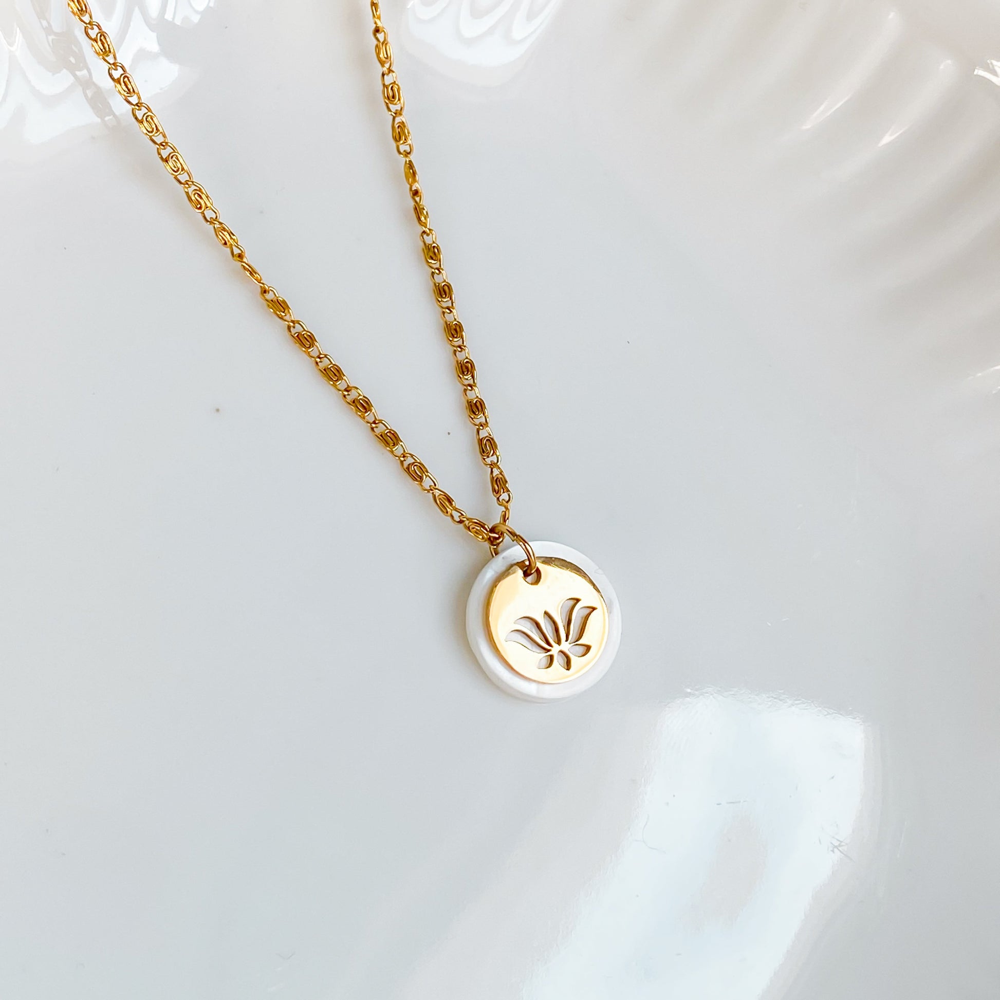 Gros plan du collier Thétis en nacre et fleur de lotus doré sur fond blanc