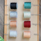Les 8 options de couleur de cordon disponibles pour les bracelets cordon personnalisables, incluant noir, blanc, gris clair, vert menthe, champagne, sarcelle, rouge bordeaux, et pêche.