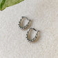 Boucles d’oreilles créoles torsadées en argent 925 Héra posées sur fond clair