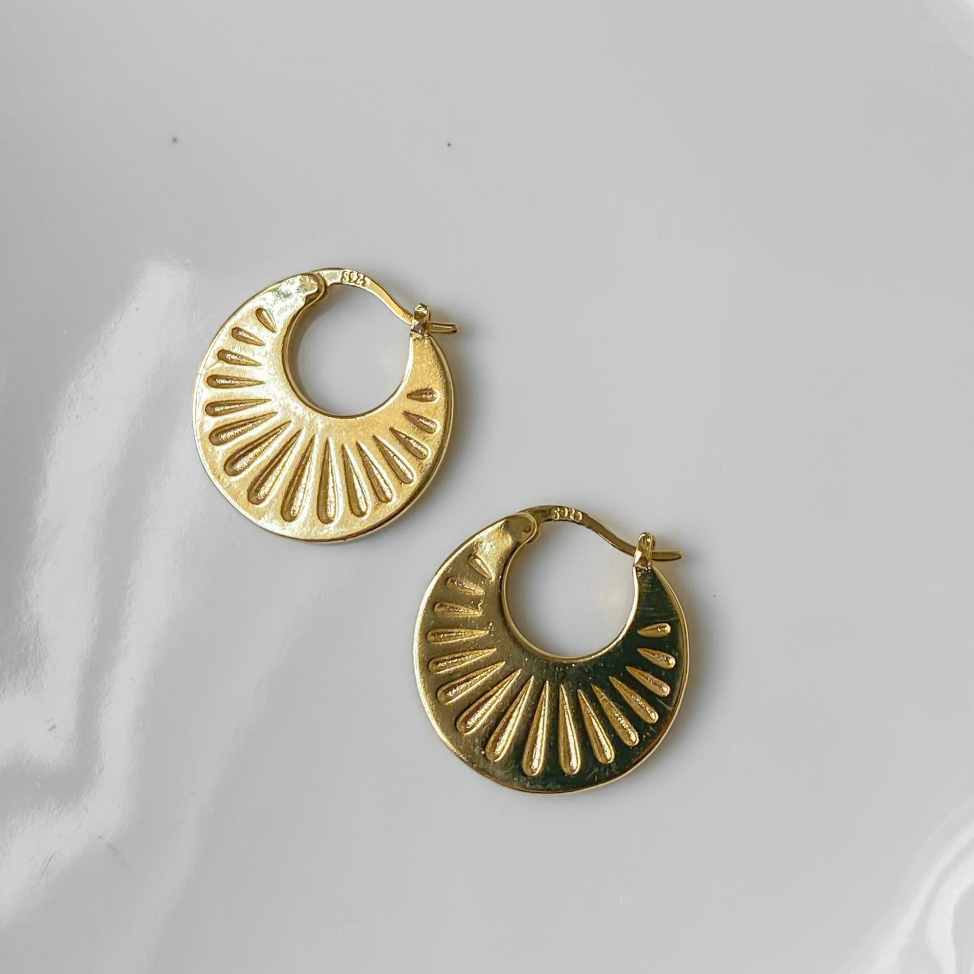 Boucles d’oreilles créoles Hélia texturées en argent plaqué or, détail du design solaire.