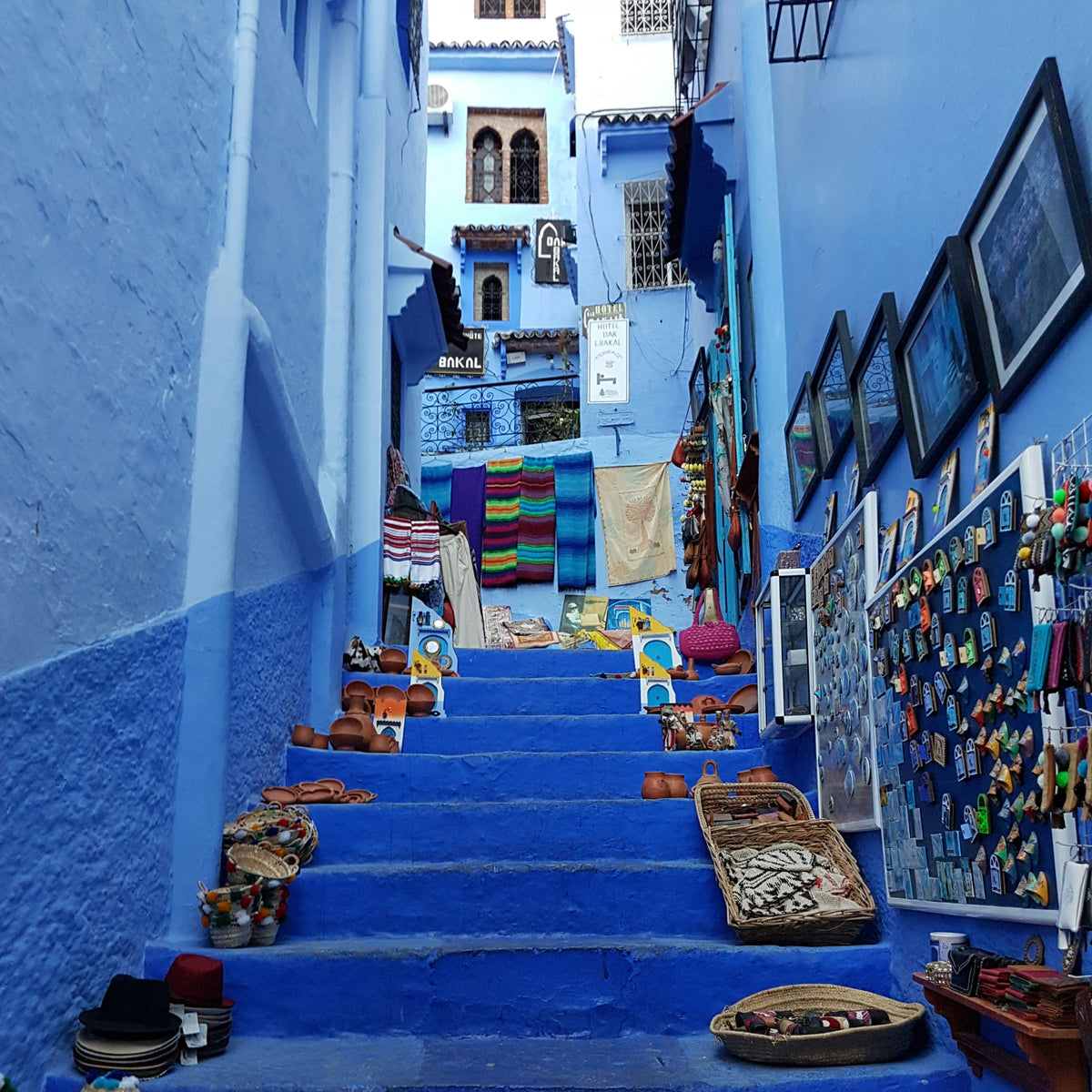 Ruelle et escaliers bleus bordés de boutiques artisanales à Chefchaouen au Maroc.